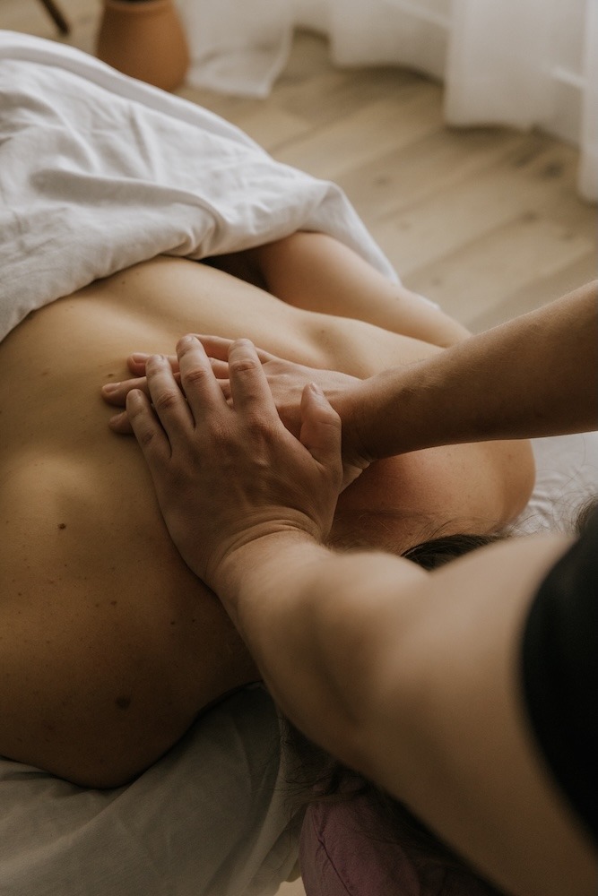 Devin Brown, Registered Massage Therapist at Triada Health Ottawa, providing therapeutic sports massage treatment on upper back
