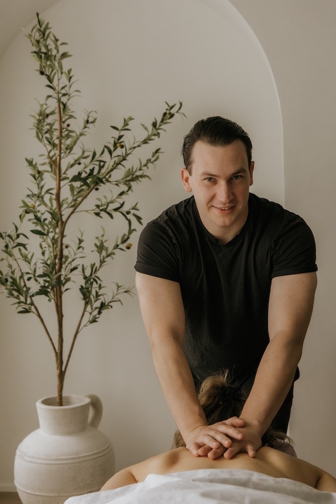 Devin Brown, Registered Massage Therapist at Triada Health Ottawa, providing deep tissue massage treatment for muscle tension from sports and weightlifting.